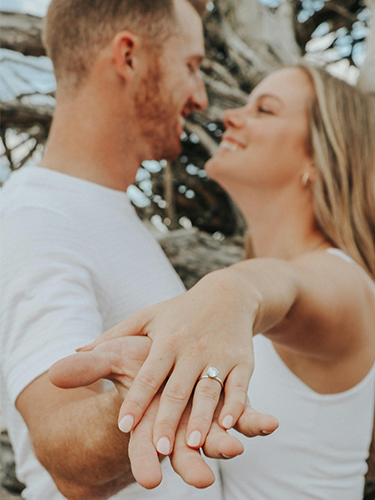 A couple holds hands happily, the woman wears a lab-grown diamond engagement ring on her hand